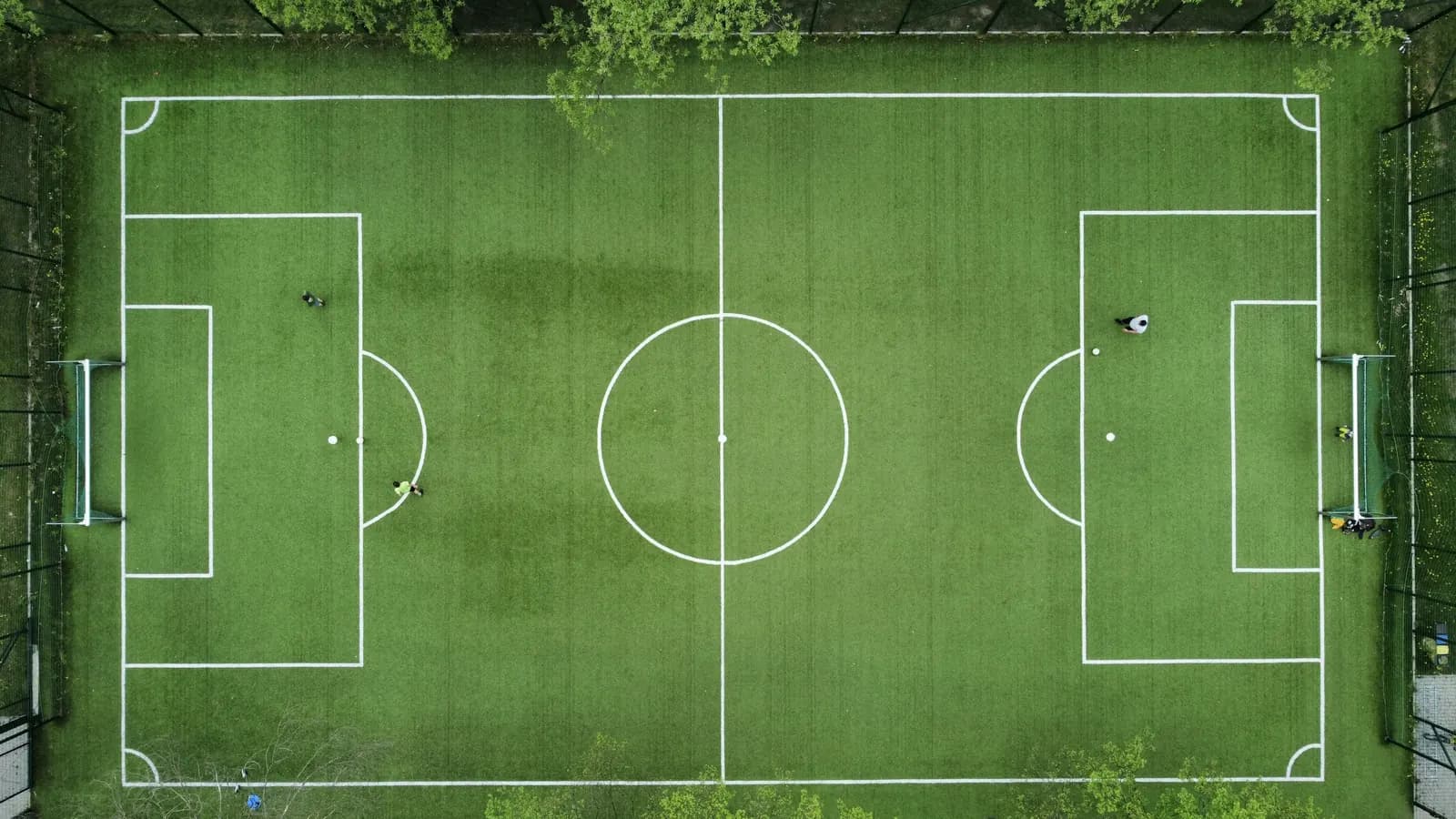 An aerial view of a small football pitch surrounded by trees