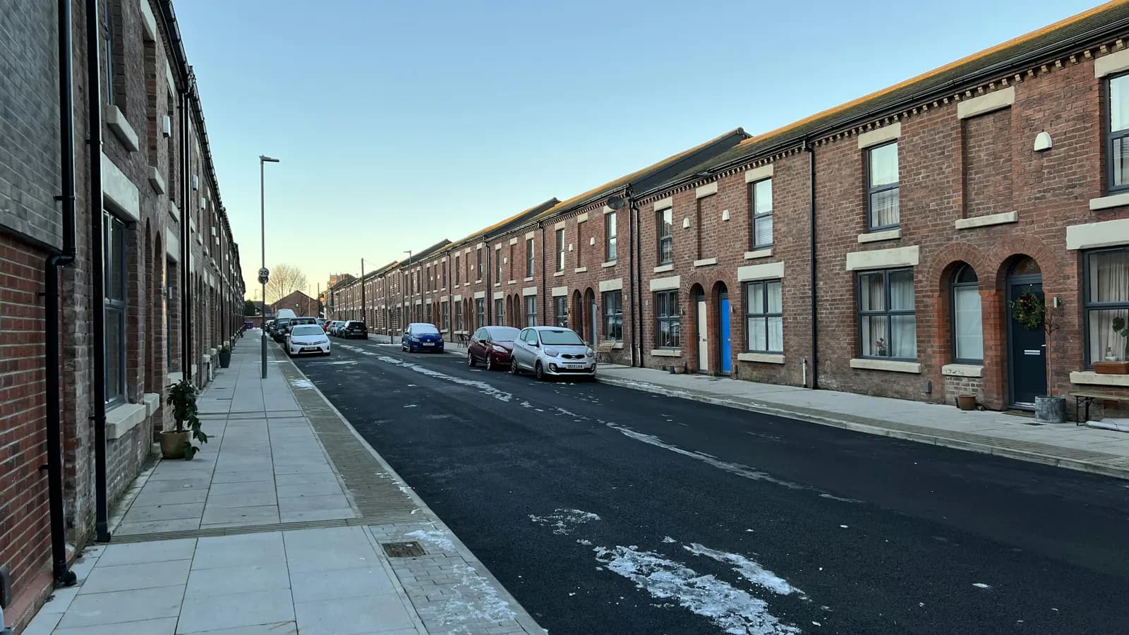 A street of red-brick terraced houses with parked cars in Liverpool