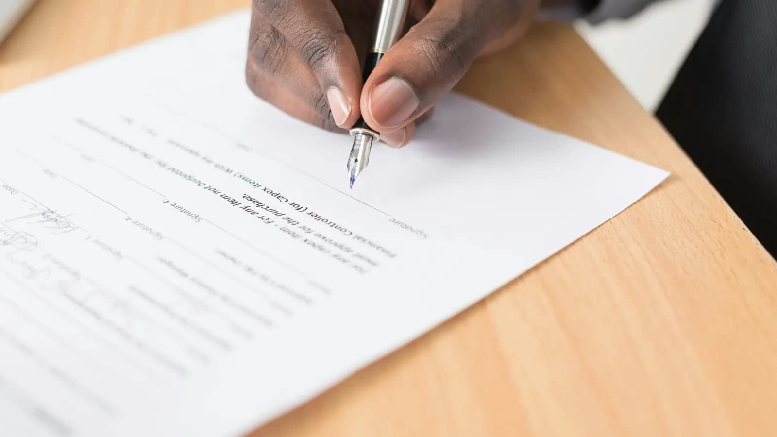 A hand signing a document with a fountain pen
